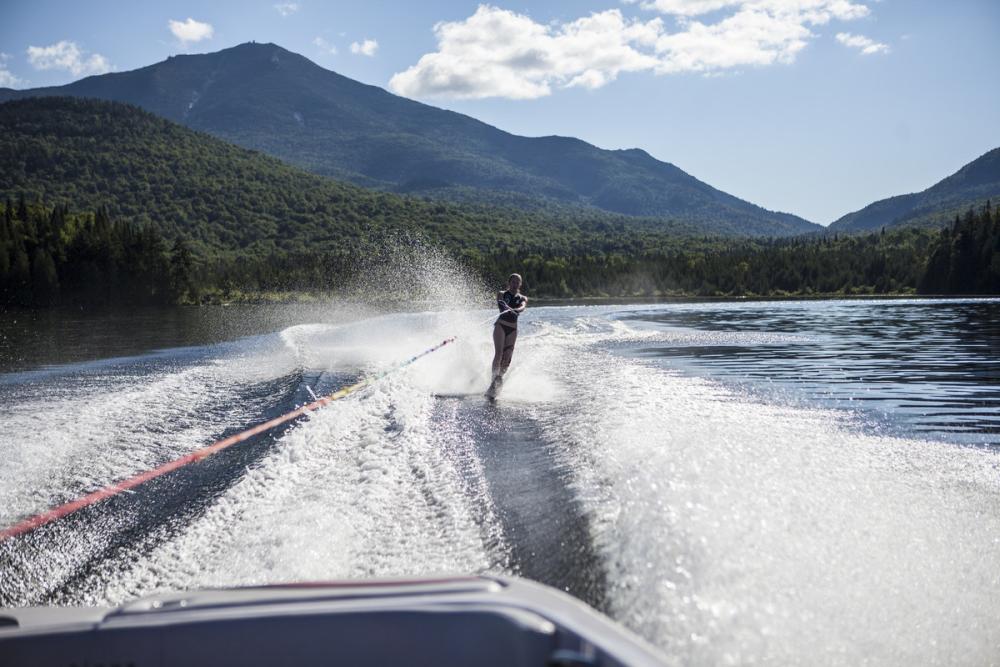 A woman waterskis on Lake Placid with mountains in the background.