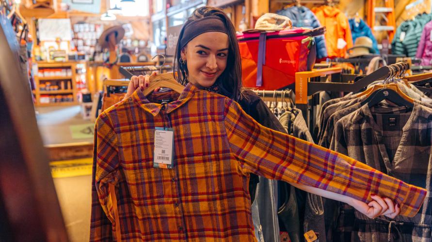 A woman looks at a flannel shirt. 