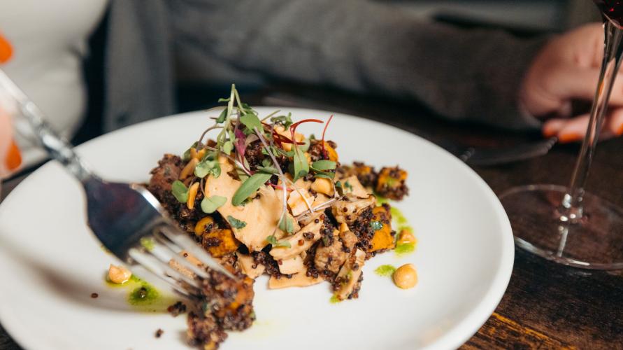 Hand holding fork grabs bit of quinoa dish