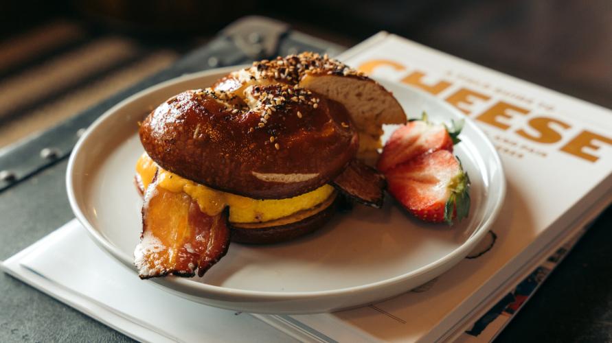 Breakfast sandwich on bagel with strawberries on plate on top of book titled 