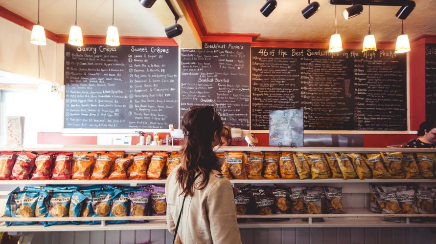 Woman looks at menu board at sandwich shop