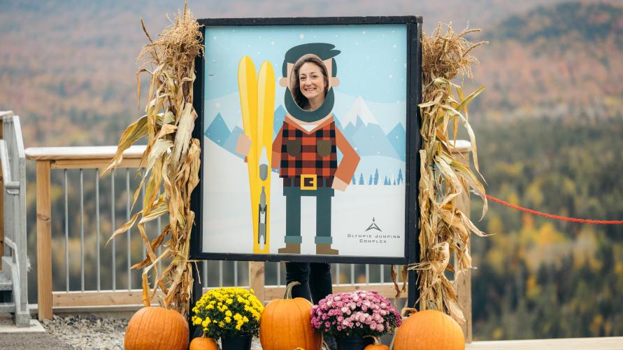 A woman poses in a frame for a fall festival.