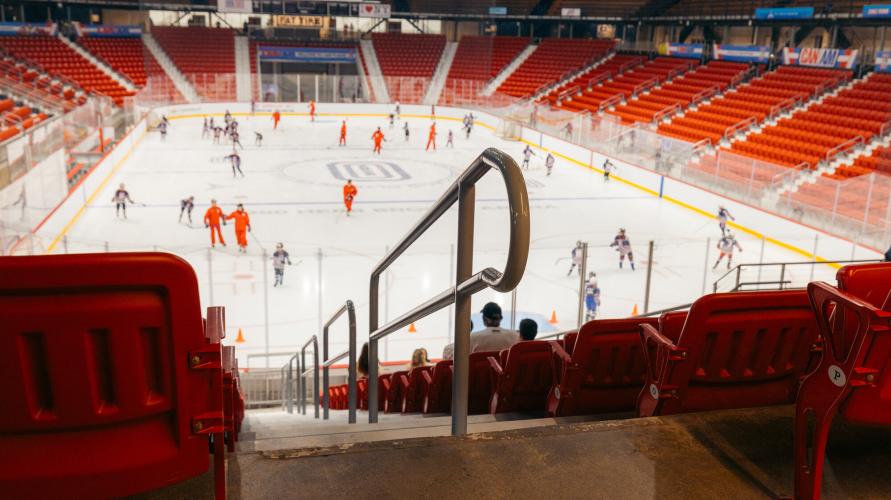 View of 1980 Herb Brooks Arena in Lake Placid from upper seats while skaters play on ice