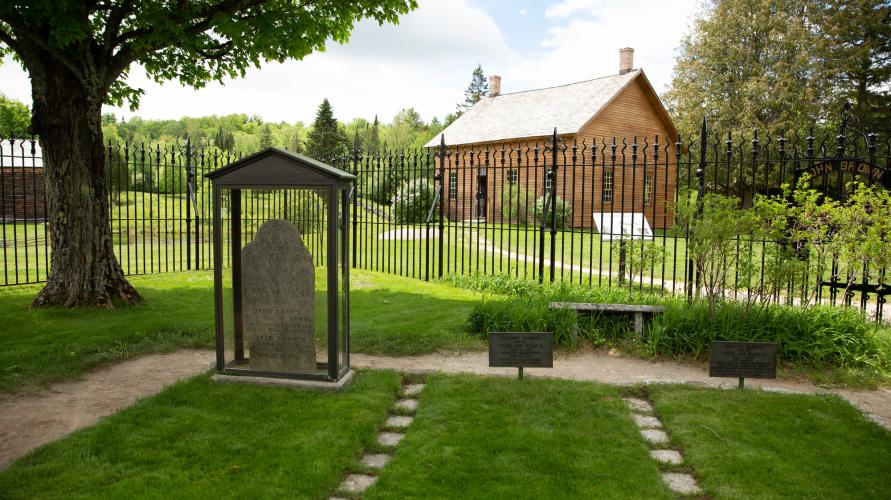 John Brown Farm cemetery with barn in background on summer day