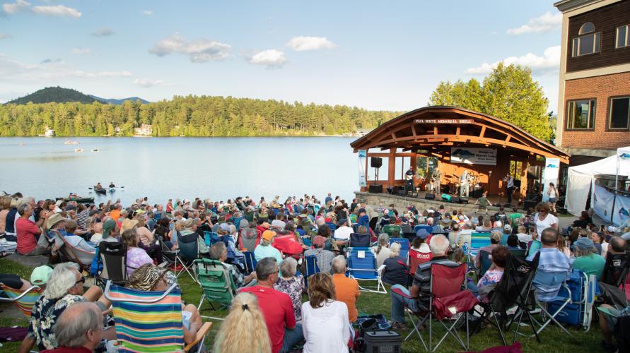 Crowd at Songs at Mirror Lake concert in Mid's Park with band shell and lake in background