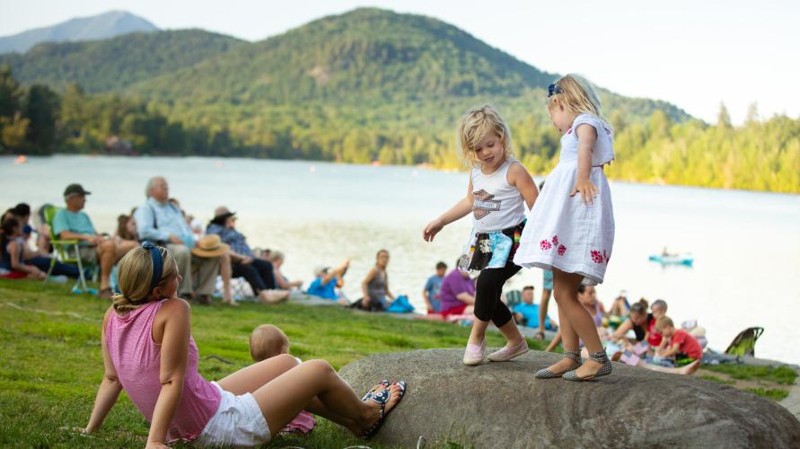 two girls dance on a rock with the lake in the background.