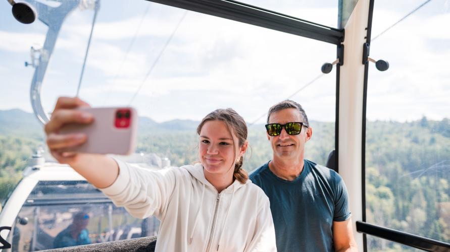 A father and daughter take a selfie in a gondola