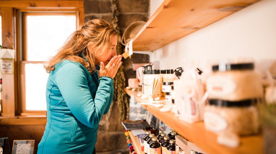 A woman smells candles in a shop. 