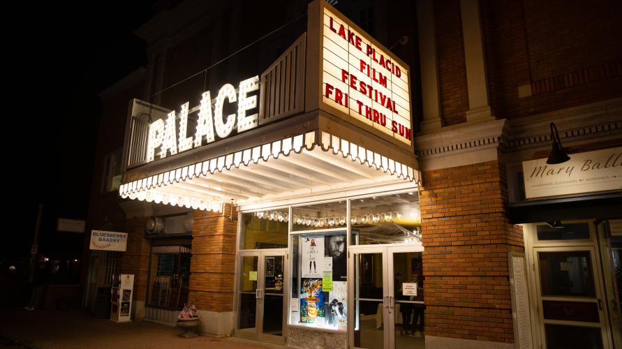 An old school movie theater at night with a lit up sign. 