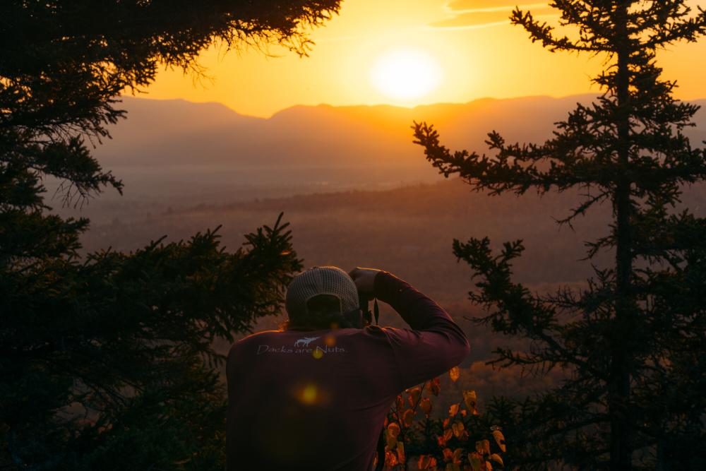 A man takes a picture of the sunset on an autumn day in the mountains.