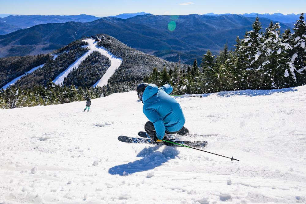 A skier in a blue puffy shredding down the mountain