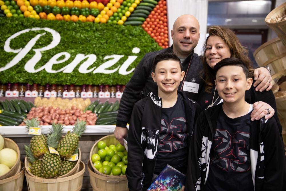 A family poses for a picture in front of a table at a conference.