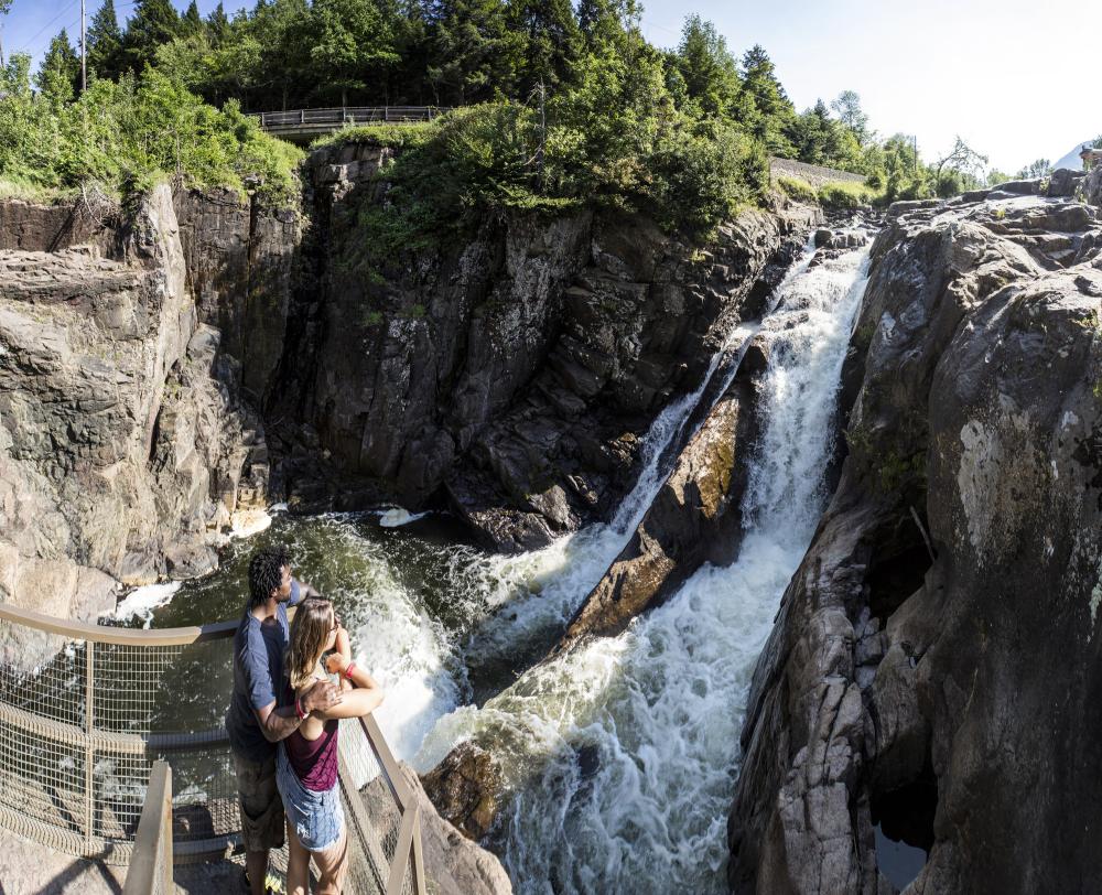 A couple looks off of a platform at a waterfall at High Falls Gorge.