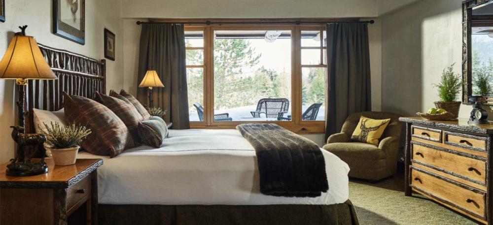 The interior of a guest room at a luxury mountain resort, featuring upscale rustic-inspired furnishings.