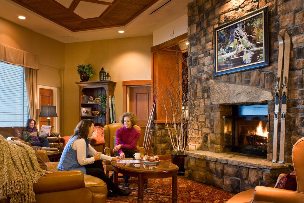 Two women chat in a hotel lounge next to a stone fireplace.