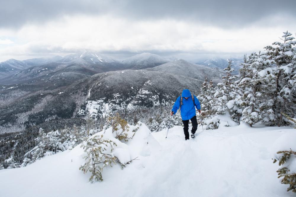 A person snowshoeing up a mountain in Keene Valley during the winter.