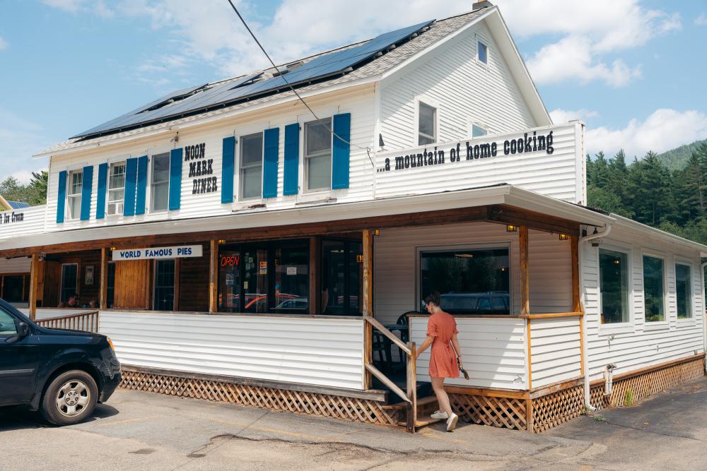 A woman walking into Noon Mark Diner during the summer.