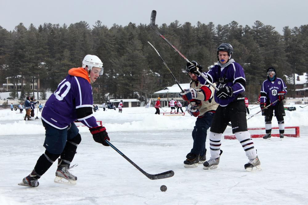 A pond hockey tournament fills several small rinks on a frozen lake.