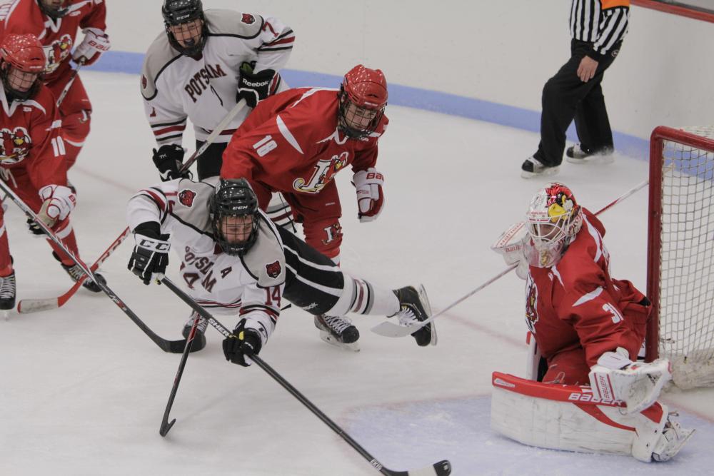 Collegiate hockey players scramble in front of the net.