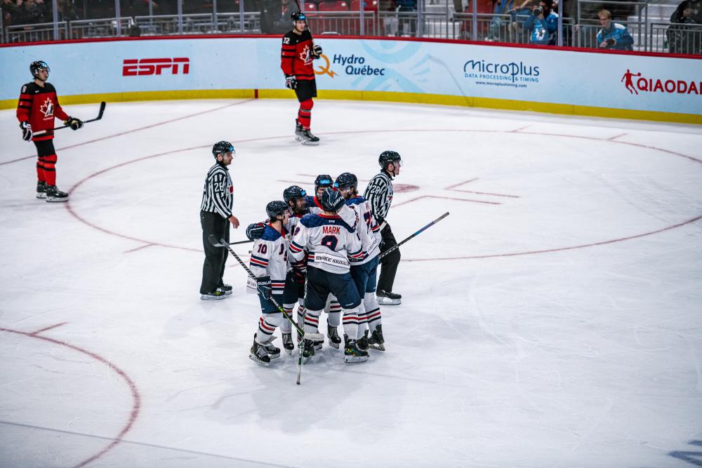 A cluster of hockey players cluster together in celebration on the ice.