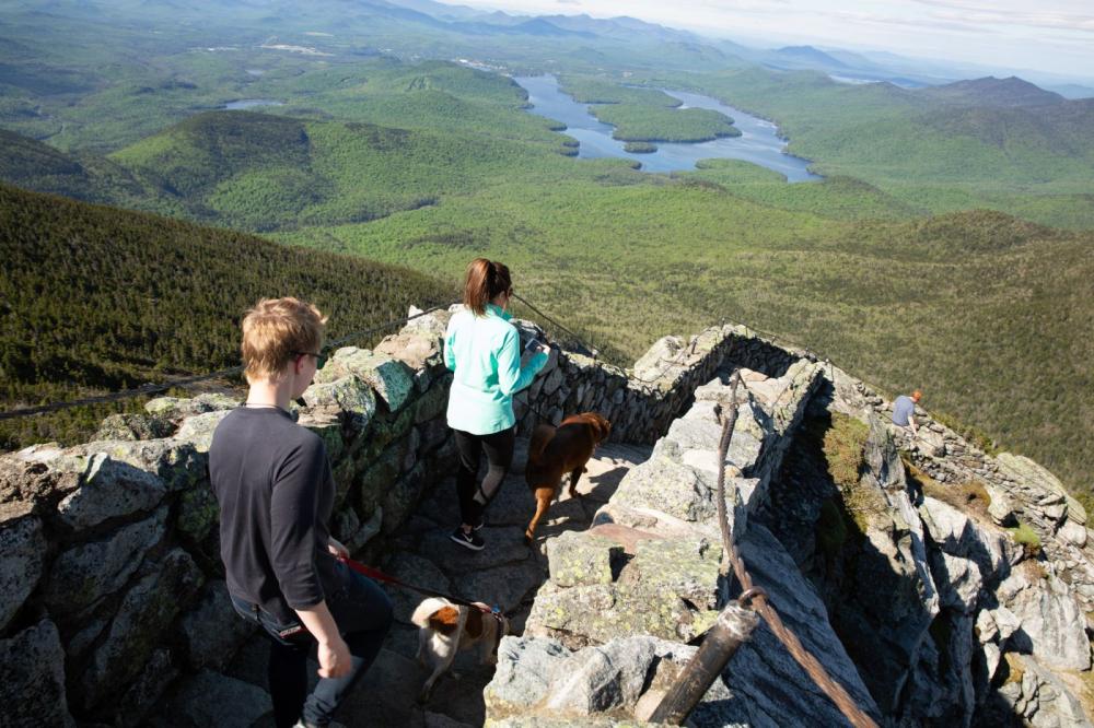 Two women walking down the stairs from the Whiteface Mountain weather station with mountains in the background.