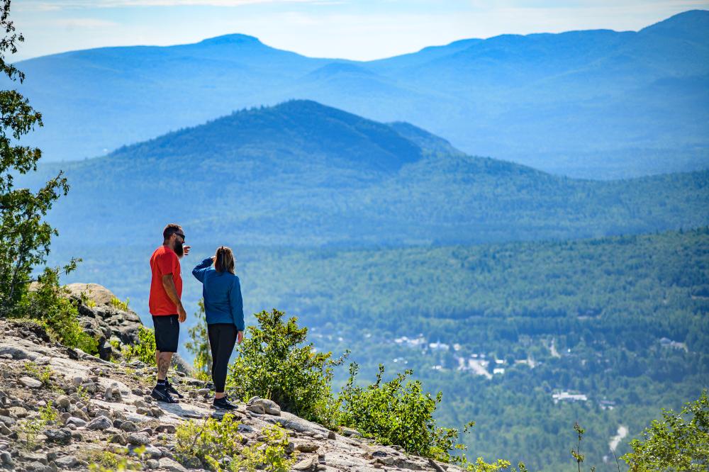 A couple enjoying the view from Cobble Lookout, one of the more popular easy hikes near Lake Placid.