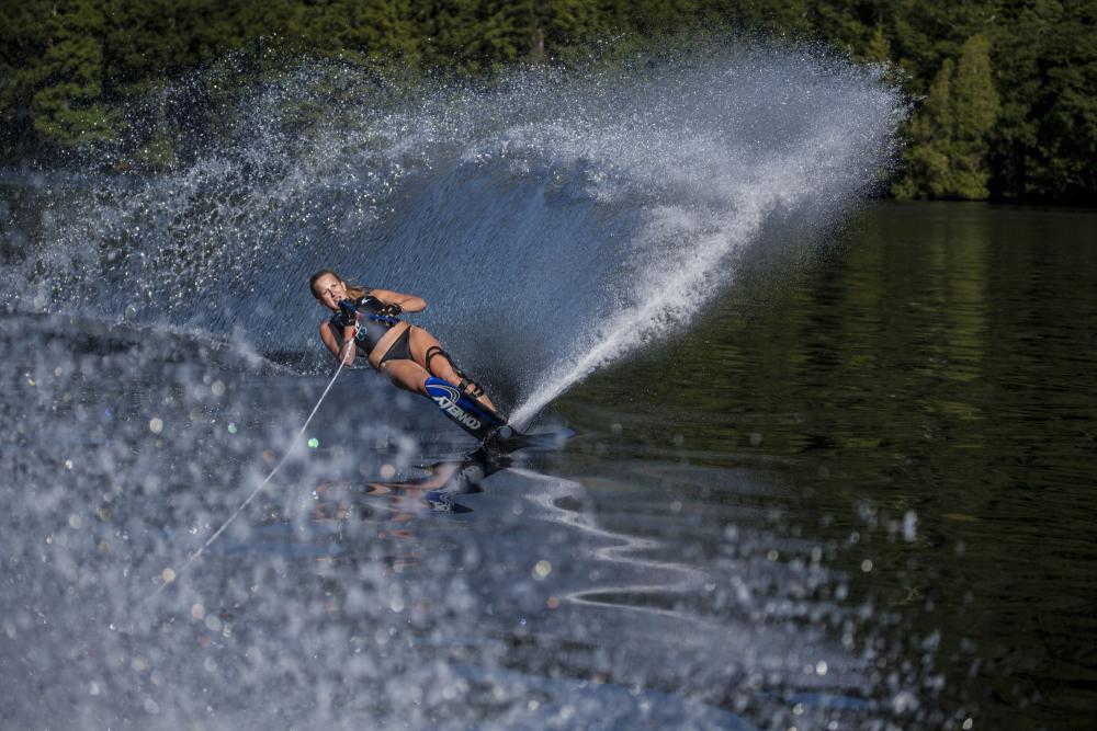 A woman on water skis carves through Lake Placid lake.