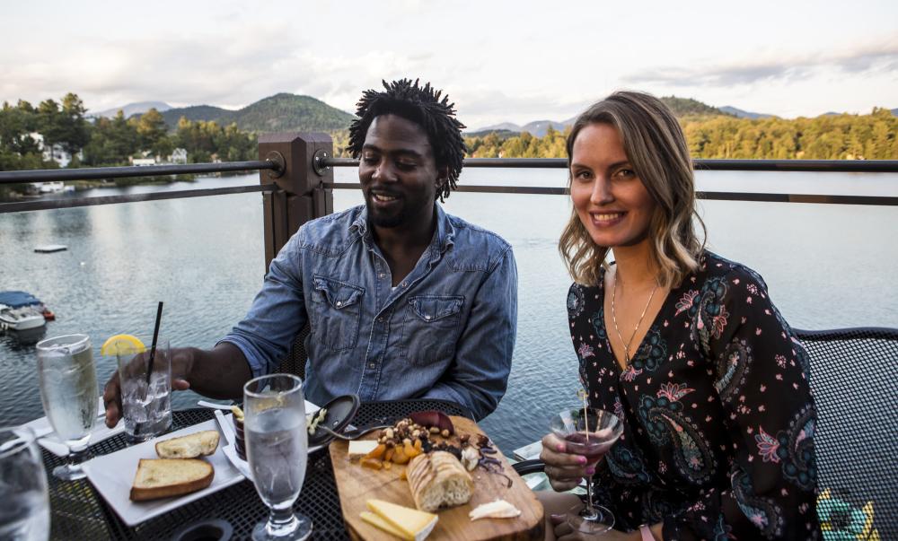 A couple enjoys a meal on the deck at Top of the Park with a lakeview.