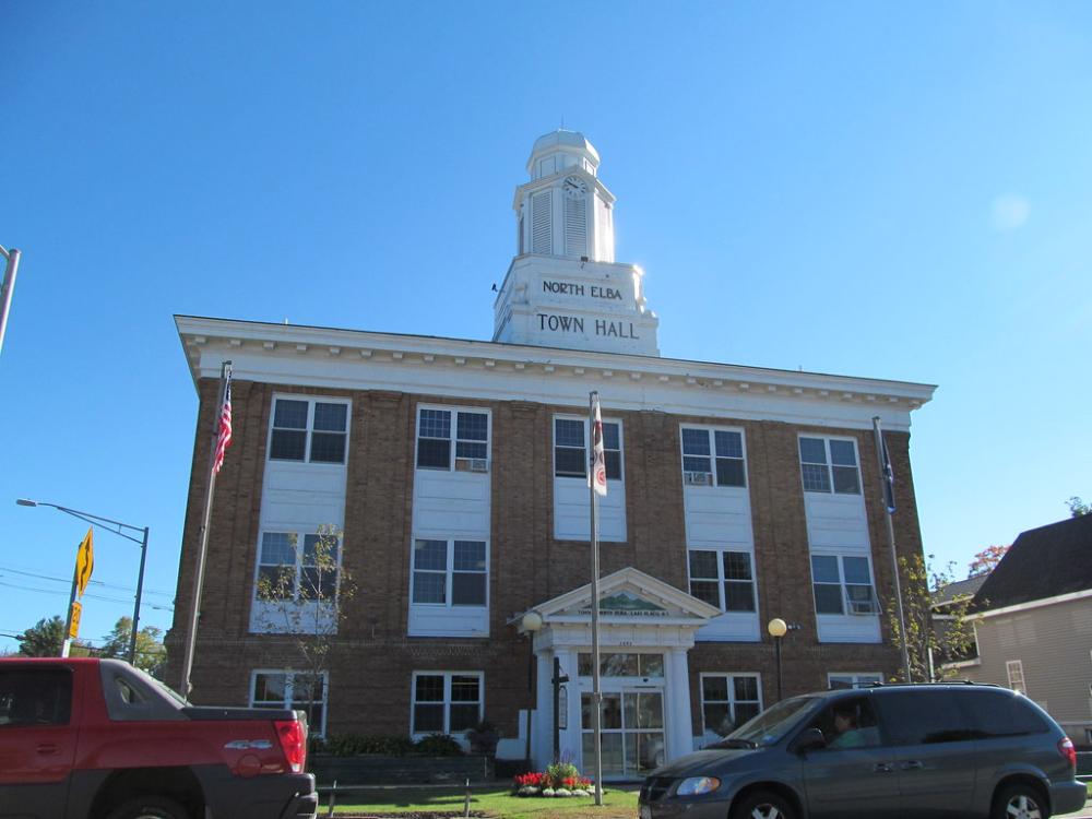 Looking up at the classic brick town hall with white bell tower.