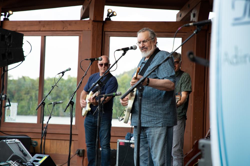 Three men perform music on a stage