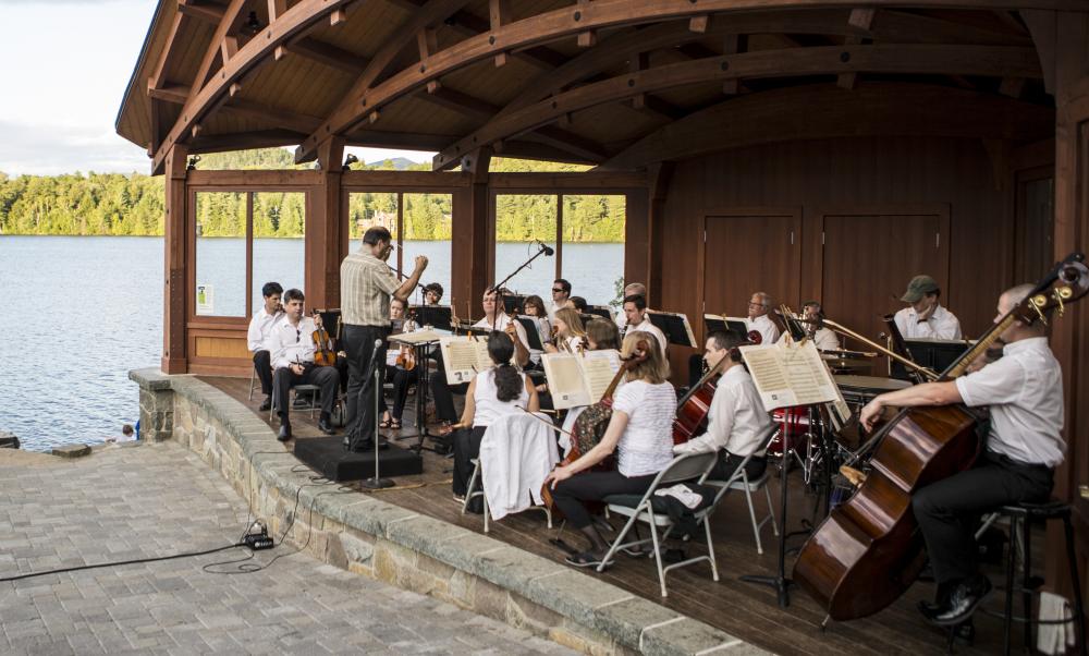 A sinfonietta performs on stage in front of Mirror Lake