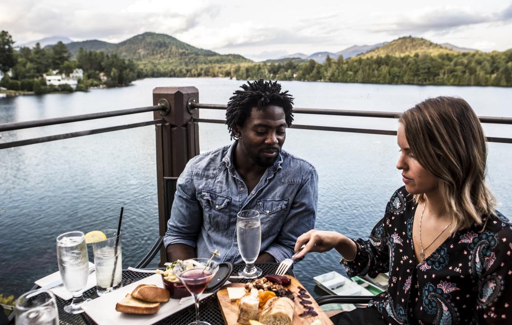 Two people sit with their drinks by the lake