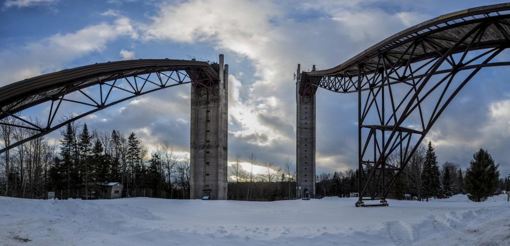 A wide view of the soaring Olympic ski jumps in Lake Placid on a snowy day.