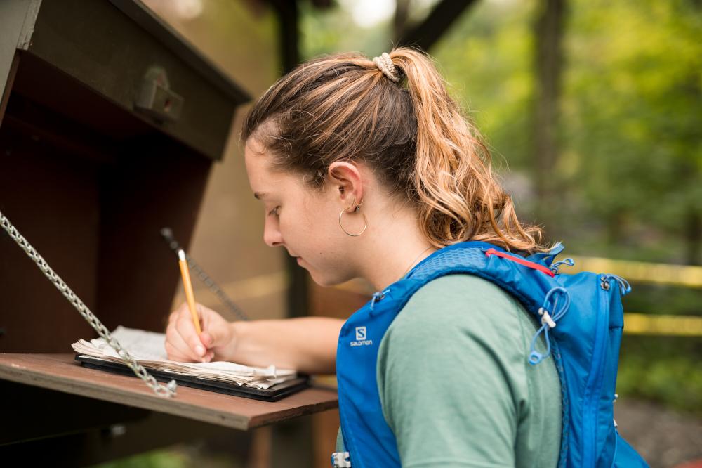 A woman signs in to a trail.