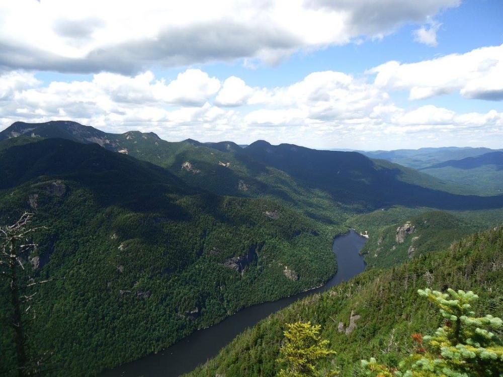 A long lake stretches out below High Peaks of green under a blue sky.