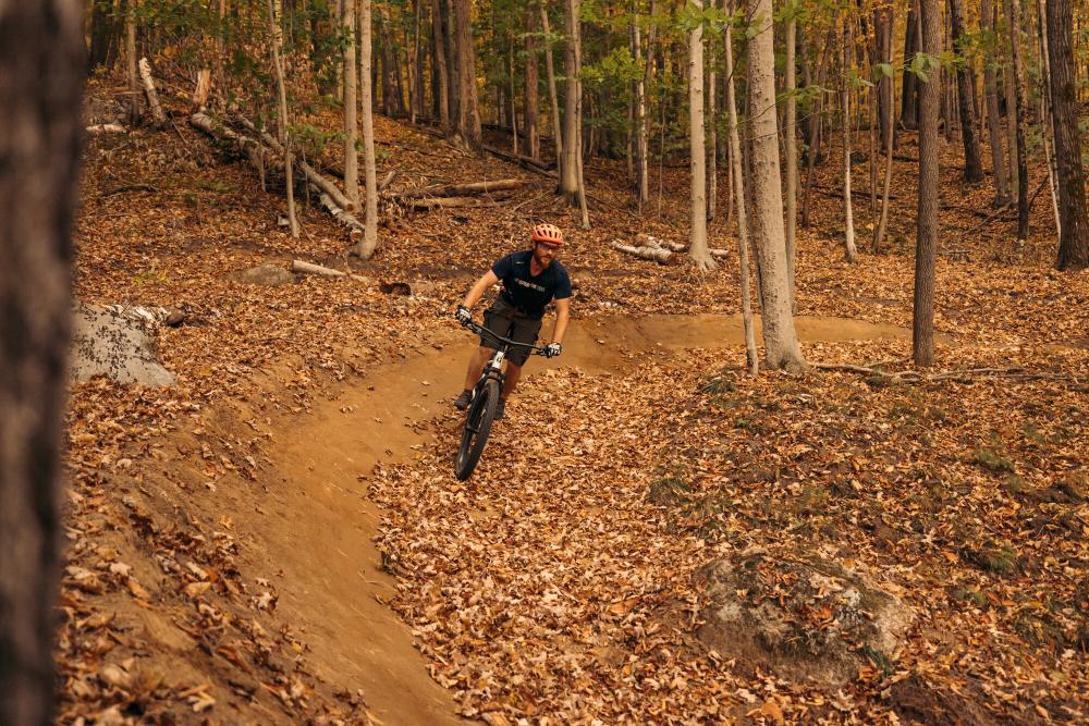 Mountain bikers rides leaf-covered trail