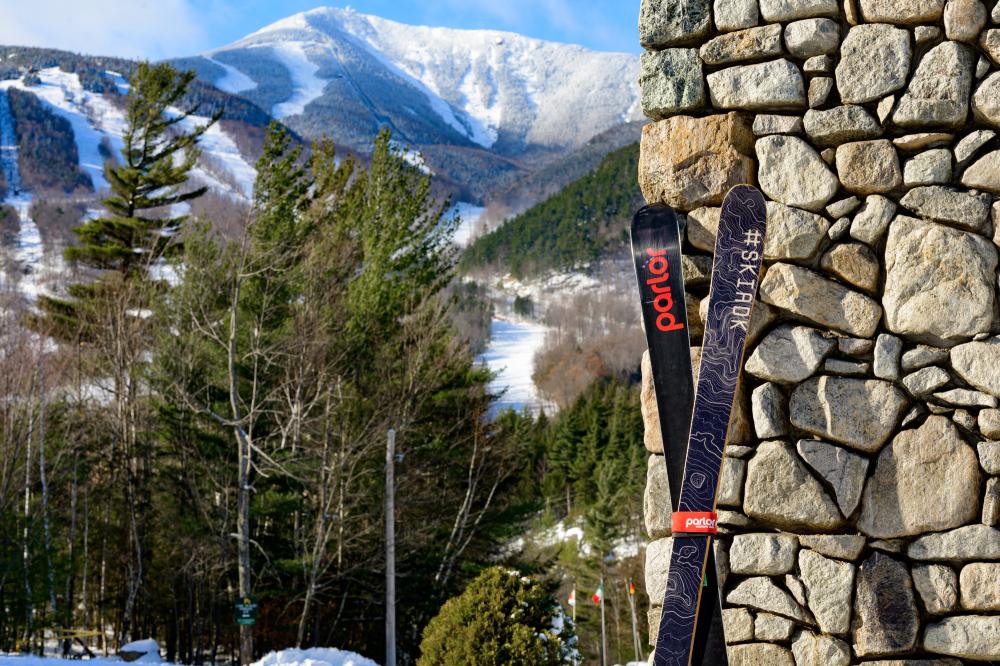 Skis propped against stone wall with Whiteface trails visible in background