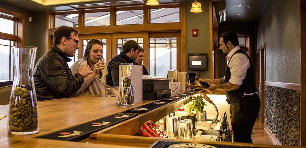 A bar tender serves patrons at a lodge-themed bar.