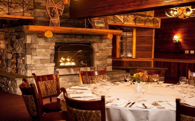 A lodge-style dining room with a large stone fireplace.