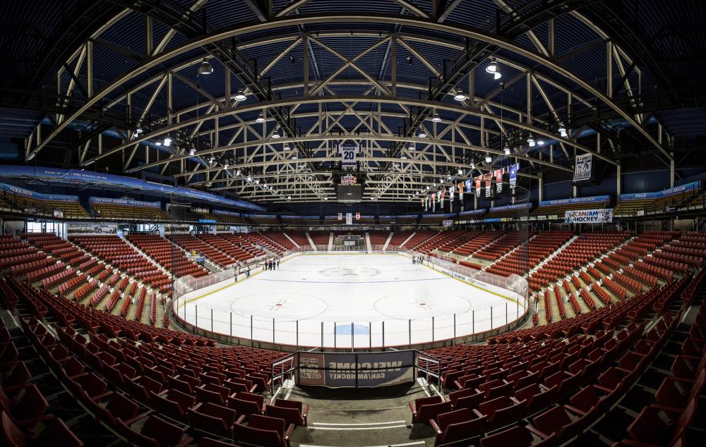 A panoramic view of a skating rink arena with red seats.