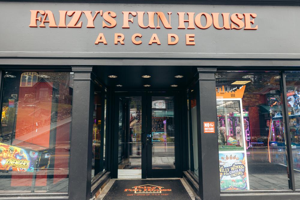 The exterior of an arcade with large glass windows. The building reads, "Faizy's Fun House Arcade"