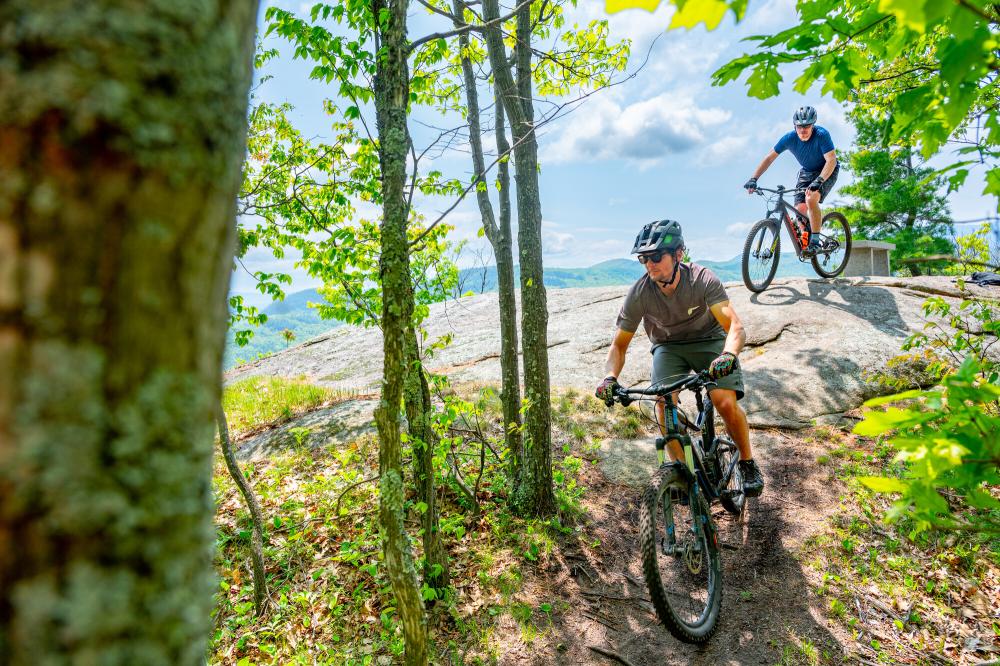 A couple mountain bikers leaving a rocky cliff