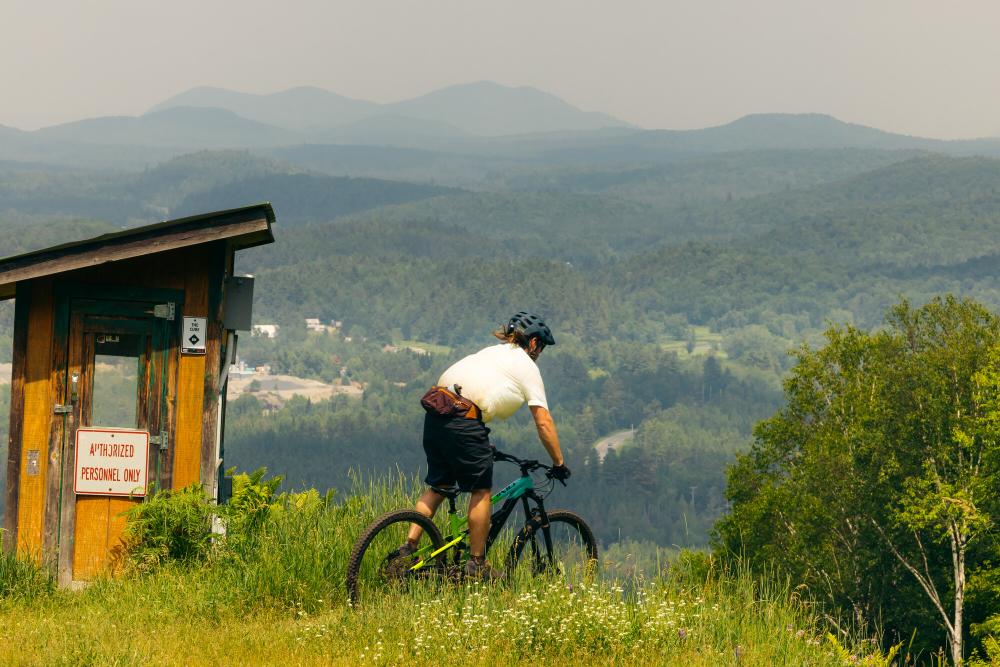 A mountain biker on top of a ski hill trail