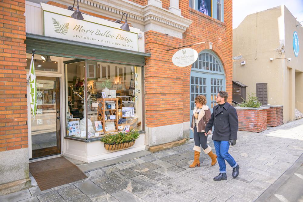 Couple walks hand in hand past shop on Main St. Lake Placid