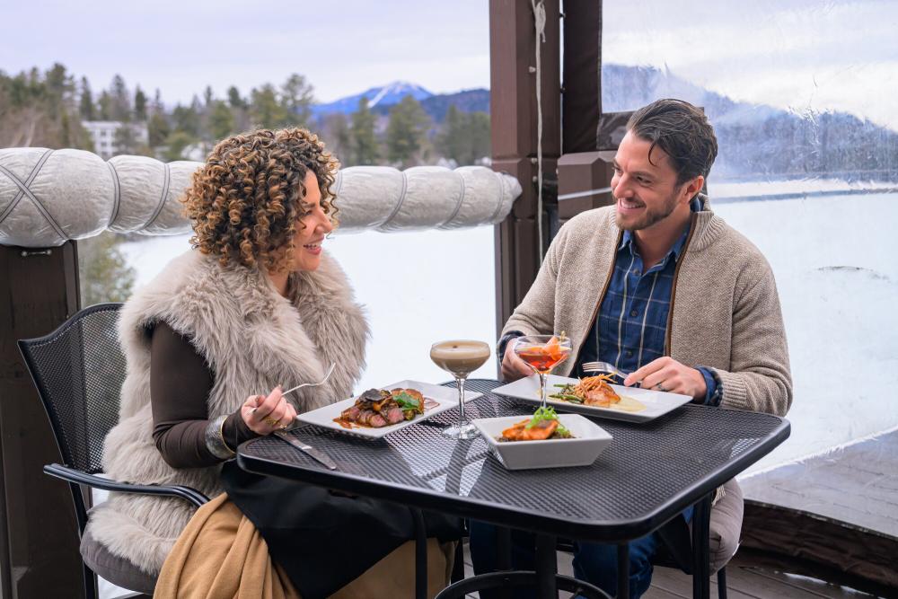 Man and woman dine on outdoor deck in winter