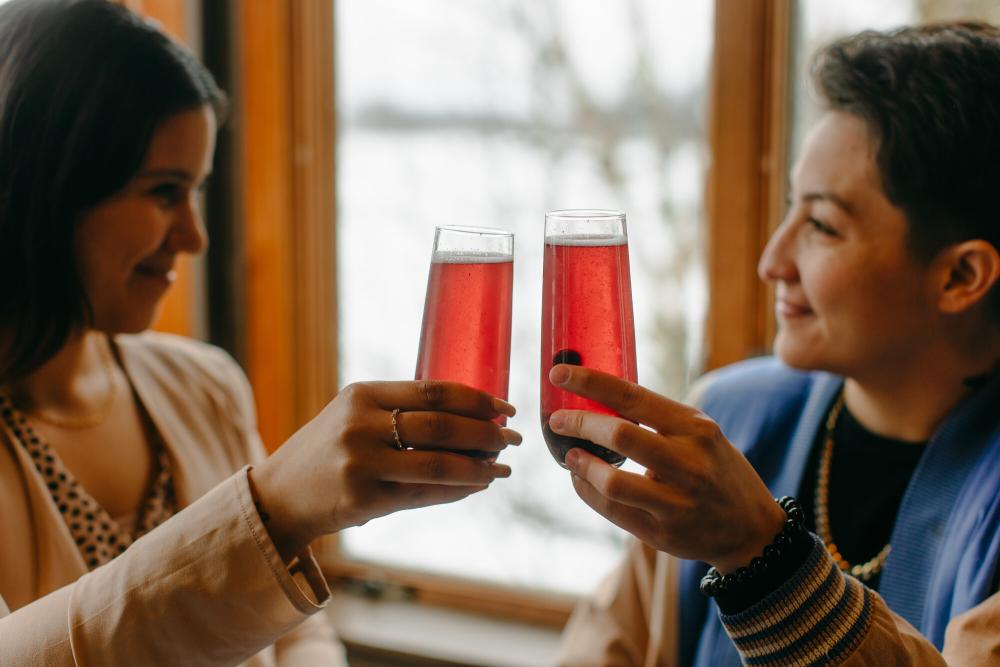 Two women cheers pink mimosas