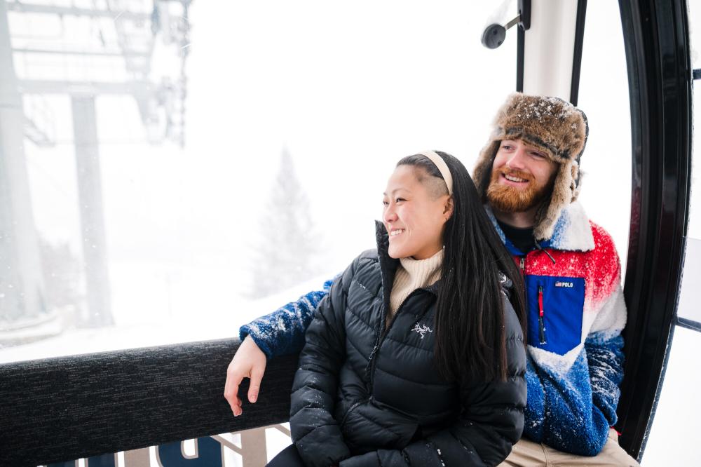 Woman leans against man riding in glass gondola