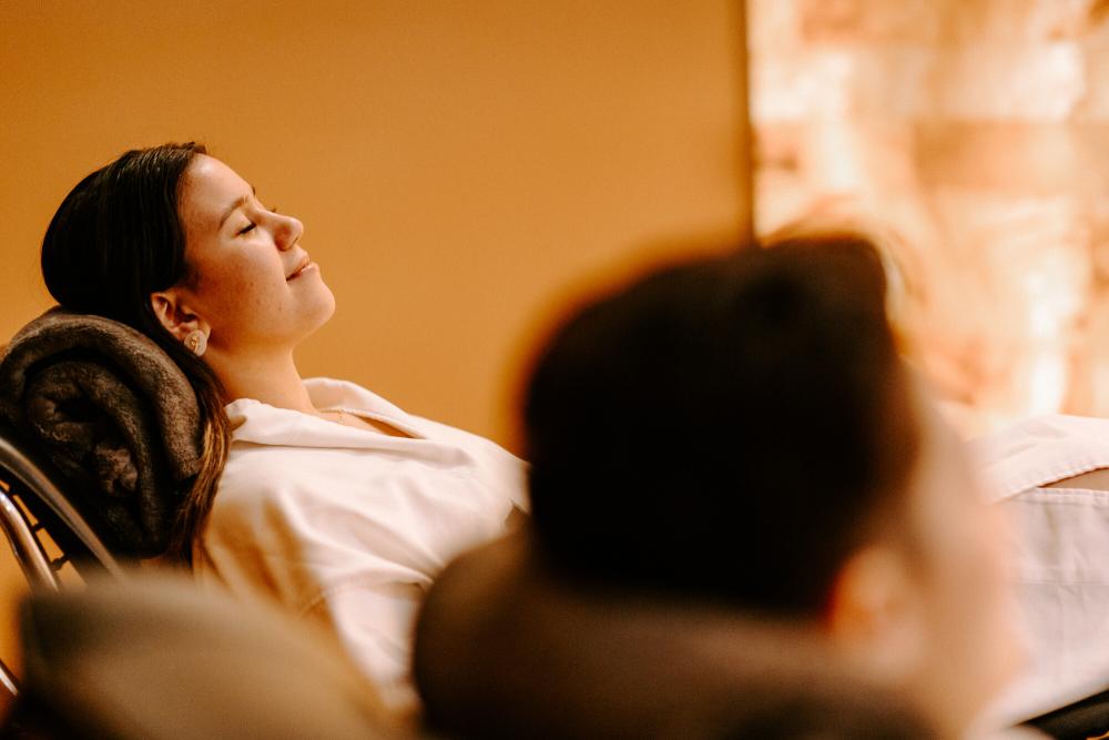 Two women relax in lounge chairs in spa robes