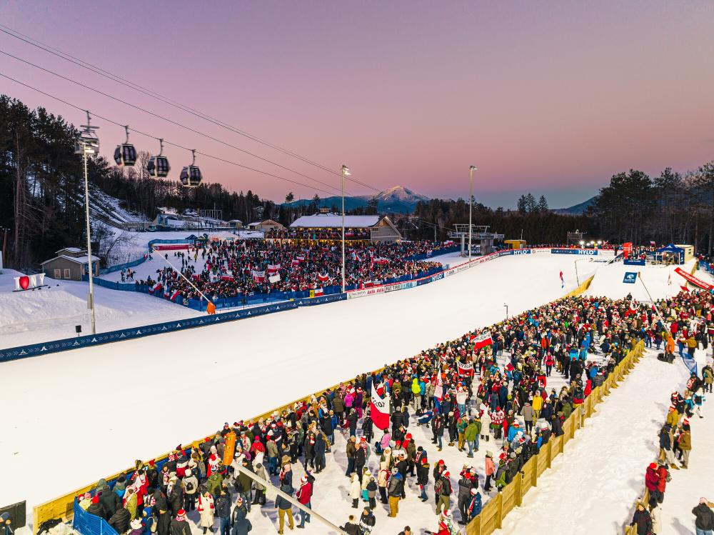 Crowd gathered at base of ski jumps at sunset