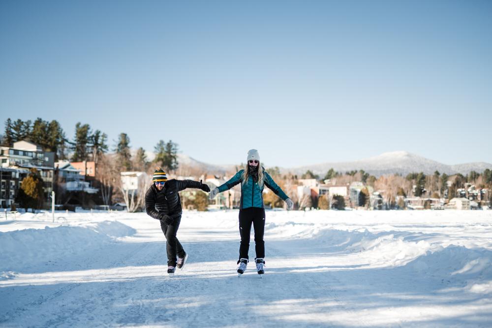 Man and woman ice skate on frozen lake